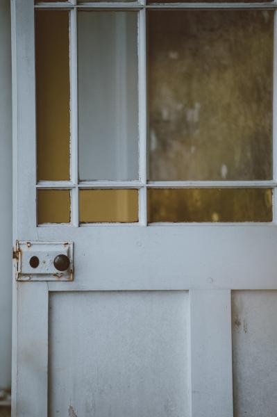An old white door with yellow window panels and a rusted lock. Photo by Annie Spratt on Unsplash