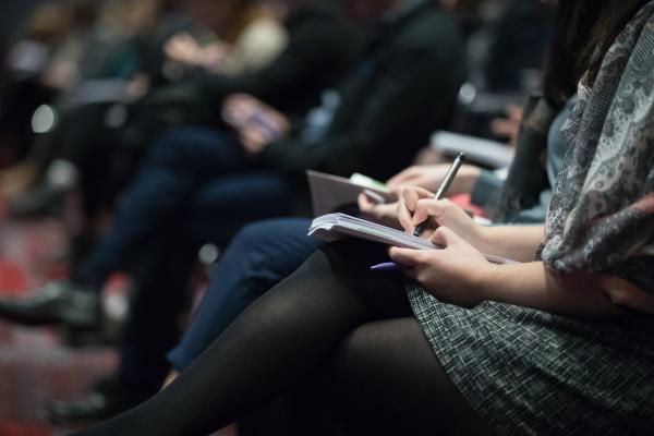 A series of laps out of focus, showing attendees at an event taking notes. Photo by The Climate Reality Project on Unsplash