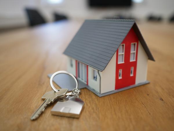 An image of a model house next to a set of keys on top of a wooden tabletop